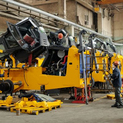 Male workers of industrial plant or repairmen checking efficiency of machines